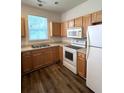 Functional kitchen featuring wood cabinets, white appliances, and durable laminate flooring at 4816 Cane Pole Ln, Summerville, SC 29485