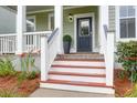Welcoming front door entrance with red painted steps, white railing, and greenery at 5242 E Dolphin St, North Charleston, SC 29405