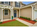 Inviting front porch with a blue door, decorative wreath, and manicured bushes at 708 Professor Dr, Ladson, SC 29456
