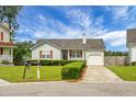 Cozy home with a tidy front yard, a porch with hanging baskets and a driveway leading to an attached garage at 8692 Bentwood Dr, North Charleston, SC 29406