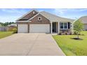 Charming home with a two-car garage, brick facade, and well-manicured lawn and driveway at 104 Wild Orchid Way, Huger, SC 29450