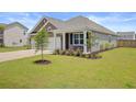 Attractive home exterior featuring a manicured lawn, young tree, and covered porch with white columns at 104 Wild Orchid Way, Huger, SC 29450