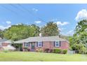 Charming brick home with green lawn, dark shutters, and mature trees under a sunny blue sky at 1237 Fort Dr, Hanahan, SC 29410
