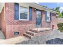 Close-up of a brick home entrance with black door and shutters, metal railing and landscaped yard at 1237 Fort Dr, Hanahan, SC 29410