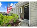 Inviting front entrance with a black door, a 'welcome' sign, and lush landscaping featuring a flowering bush at 141 Sweet Cherry Ln, Summerville, SC 29486