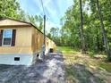 A single-story dwelling featuring light siding, nestled amidst verdant trees, with a lengthy driveway and outdoor unit at 149 Old Red Hill Rd, Ridgeville, SC 29472