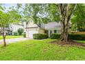 Inviting home showcasing a green lawn and mature trees, framing the charming exterior with a garage at 202 Chandler Dr, Ladson, SC 29456