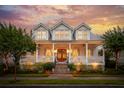 Charming two-story home with a brick staircase and a welcoming front porch beneath a colorful sunset sky at 371 Bridgetown Pass, Mount Pleasant, SC 29464