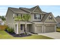 Two-story home showcasing neutral siding, brick accents, a two-car garage and a beautifully landscaped front yard at 528 Fern Tree Dr, Summerville, SC 29486
