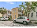 Charming yellow two-story home with a front balcony and an adjacent silver car at 10 Trapman St, Charleston, SC 29401