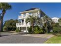 Beautiful 3-story home with dual balconies, palm trees, and a private driveway at 109 Carolina Blvd, Isle of Palms, SC 29451
