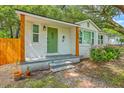 Charming house with a well-maintained yard, stone walkway, a green door, and a white brick facade at 1188 Camden St, North Charleston, SC 29405