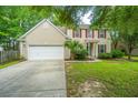 Charming two-story home with beige siding, red shutters, a well-manicured lawn, and an attached two-car garage at 1629 Jorrington Street St, Mount Pleasant, SC 29466