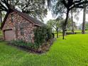 View of a brick detached garage with beautiful surrounding green grass, plants, and trees at 1807 Perch Rd, Moncks Corner, SC 29461