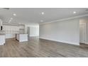 Open-concept living room with wood flooring and white trim, leading to the kitchen area at 214 Bilge Rd, Ridgeville, SC 29472