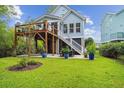 Spacious backyard with a wooden deck, stairs, mature trees, and a manicured lawn at 542 Amalie Farms Dr, Charleston, SC 29492
