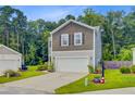 Exterior of home showing 2-car garage, neutral siding, and small landscaped garden at 9808 Wooden Pestle Way, Ladson, SC 29456