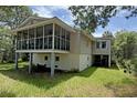 Exterior view of a raised home featuring a screened porch and mature landscaping at 1014 E Cooper Ave, Folly Beach, SC 29439