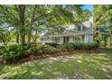 Charming home with a cozy front porch, lush landscaping, and mature trees in a well-maintained yard at 202 Woodbridge Dr, Summerville, SC 29486