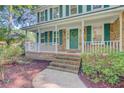 Inviting front porch with brick steps, white railing, green door, and lush landscaping at 303 High Grove Rd, Summerville, SC 29485