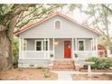 Charming single-story home featuring a cozy front porch, red door, and mature trees at 317 Bay St, Walterboro, SC 29488