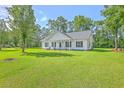 Wide view of a cozy house displaying a well-manicured lawn, mature trees, and white wooden siding at 326 Turner Ln, Round O, SC 29474