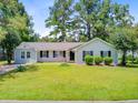 Charming one-story home featuring a well-kept lawn, complemented by green shrubs and tall trees in a serene setting at 405 Amberjack Way, Summerville, SC 29485