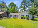 Inviting single-story home with a lush green lawn, mature trees, and manicured shrubs in a desirable neighborhood at 405 Amberjack Way, Summerville, SC 29485