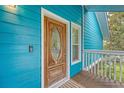 Inviting stained wood front door with decorative glass, teal siding, and covered porch at 4636 Ashley View Ln, North Charleston, SC 29405