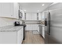 Modern kitchen featuring stainless steel appliances, white cabinets, granite countertops, and hardwood floors at 5904 Oak Street, Hanahan, SC 29410