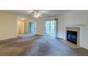 Spacious living room with a cozy fireplace, ceiling fan and sliding glass doors leading to outdoor space at 6280 Rolling Fork Rd # 302, North Charleston, SC 29406
