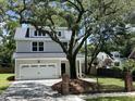 Charming two-story home featuring a two-car garage, white exterior, and a beautiful mature tree in the front yard at 641 Magnolia Rd, Charleston, SC 29407