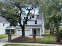 Charming two-story home featuring a two-car garage, white exterior, and a beautiful mature tree in the front yard at 641 Magnolia Rd, Charleston, SC 29407