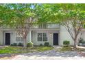 Charming two-story condo with white siding, a walkway, mature trees, and a private second-story balcony at 7814 Nummie Ct, North Charleston, SC 29418