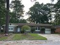 Single-story brick home with a well-maintained lawn and mature trees providing shade at 8334 Witsell St, North Charleston, SC 29406