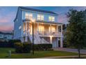 Charming two-story coastal home with a welcoming front porch and a warm glow at dusk at 1464 Stratton Pl, Mount Pleasant, SC 29466