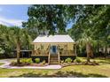 Beautiful single-story home with a metal roof and inviting porch, surrounded by mature palm trees and landscaping at 1515 N Lakeshore Dr, Mount Pleasant, SC 29466