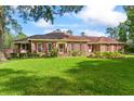 Spacious front yard with mature trees framing a lovely brick home with manicured lawn at 1551 Hutton Pl, Charleston, SC 29407