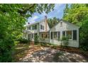 White two-story home with black shutters and brick driveway surrounded by mature trees at 6 Sayle Rd, Charleston, SC 29407