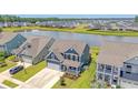 An aerial view capturing a community with lake views and beautiful blue home with a well-manicured lawn at 602 Yellow Leaf Ln, Summerville, SC 29486