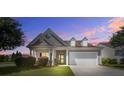 Charming one-story home showcasing manicured lawn, beautiful landscaping, and a two-car garage at twilight at 129 Schooner Bend Ave, Summerville, SC 29486