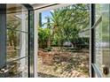 View from inside the house looking out to a brick patio with seating surrounded by lush landscaping at 22 Lamboll St # C, Charleston, SC 29401