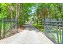 Gated entrance with a long gravel driveway leading to a beautiful, tree-lined property at 2494 Cape Rd, Johns Island, SC 29455