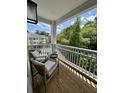 Relaxing outdoor balcony with seating, views of lush greenery, and a glimpse of nearby buildings at 400 Bucksley Ln # 301, Charleston, SC 29492