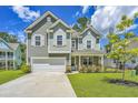 Inviting two-story home featuring a covered porch and well-maintained landscaping at 104 Limpkin Ln, Summerville, SC 29483