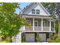 Charming two-story home featuring a welcoming front porch, two-car garage, and lush landscaping at 129 Martins Point Dr, Wando, SC 29492