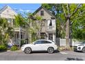 Charming two-story home with white car parked, surrounded by lush trees and a white picket fence at 176 Smith St, Charleston, SC 29403