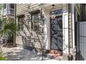 Close-up of a stylish home entrance with a gray door, brick steps, and hanging lantern, shaded by a palm tree at 176 Smith St, Charleston, SC 29403
