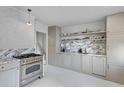 Modern kitchen with stainless steel range, custom cabinets, marble counters and backsplash, and white painted floors at 176 Smith St, Charleston, SC 29403