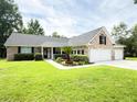 Charming brick home featuring a manicured lawn, three-car garage, and lush landscaping at 1804 Bass Rd, Moncks Corner, SC 29461